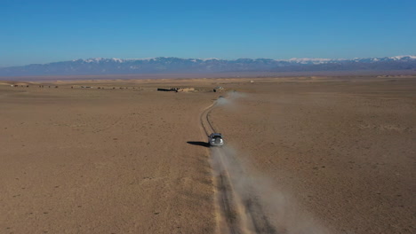 Aerial-tracking-drone-shot-of-a-car-caravan-traveling-in-the-Charyn-Canyon,-Kazakhstan