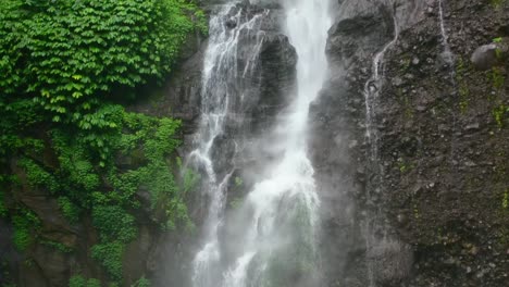 Antenne-Des-Mächtigen-Wassers,-Das-Von-Den-Mit-Moos-Bedeckten-Felsen-Im-Dschungel-In-Bali,-Indonesien,-Fällt
