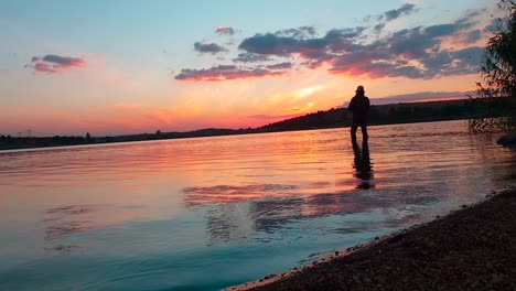 Eine-Frau,-Die-Kurz-Nach-Einem-Spektakulären-Sonnenuntergang-In-Einem-Ruhigen-See-Fische-Fängt