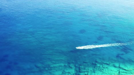 Luftdrohnenansicht-Des-Bootes,-Das-Klares-Wasser-Auf-Der-Insel-Ios-In-Griechenland-Zerquetscht