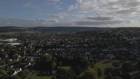 Aerial-view-of-Portishead-parish-near-Bristol,-drone-moving-forward-above-the-houses-and-the-green-gardens,-blue-and-cloudy-sky-in-the-background