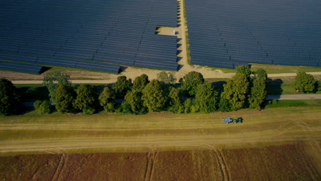 Aerial-Overhead-View-Of-Large-Scale-Solar-Panel-Farm-With-Tractor-Driving-Past