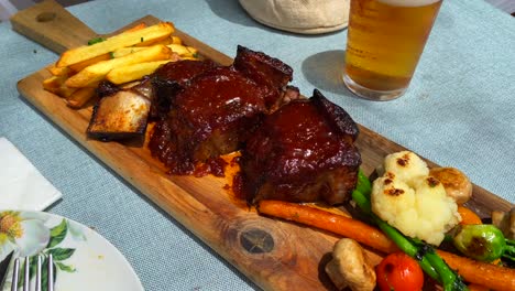 Tender-slow-cooked-beef-ribs-in-bbq-sauce-with-french-fries-and-vegetables,-tasty-food-in-a-restaurant,-4K-shot