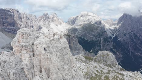 Mountaineer-descending-mountain-peak,-wide-cinematic-aerial-shot-at-Tre-Cime