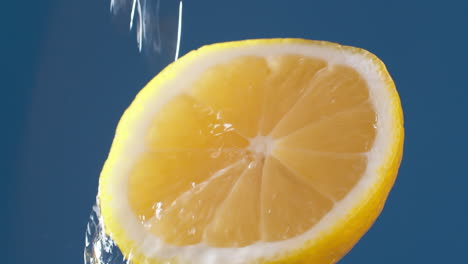 Makroaufnahme-In-Zeitlupe-Von-Fließendem-Wasser-Aus-Zitronenscheibe-Auf-Blauschwarzem-Hintergrund