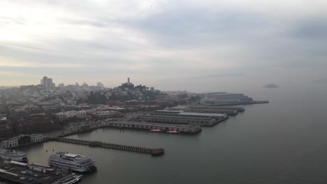 Aerial-view-of-piers-at-the-Embarcadero,-in-cloudy-San-Francisco,-USA---pan,-drone-shot