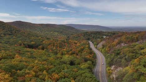 An-aerial-view-high-over-the-mountains-in-upstate-NY-during-the-fall,-on-a-nice-day-with-white-clouds