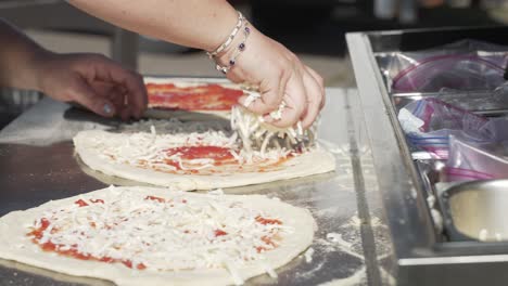 Close-up,-woman's-hands-spreading-mozzarella-cheese-on-fresh-pizza-dough-in-slow-motion