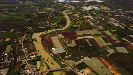 Aerial-tilt-up-flying-over-rural-area-near-river-on-sunny-day,-Tu-Tra,-Vietnam