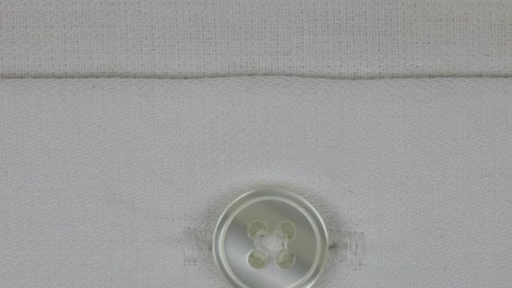 Plastic-Button-With-Four-Holes-In-White-Soft-Fabric