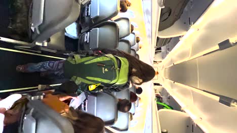 Female-passenger-with-backpack-walking-down-the-aisle-in-an-aircraft,-backpacker-boarding-a-plane