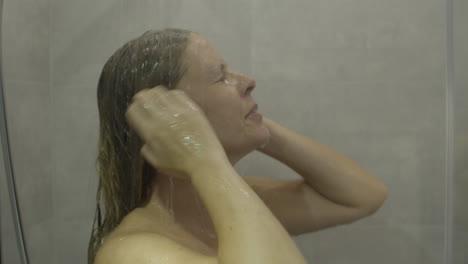 Woman-stepping-under-a-running-shower-and-cleansing-her-hair-and-face