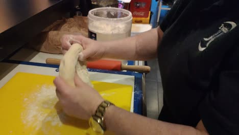 the-hands-of-the-worker-with-golden-clock-kneading-dough-with-wheat-flour-to-prepare-bread-in-the-oven-in-her-work-area,-Blocked-shot,-Orders,-Galicia,-Spain
