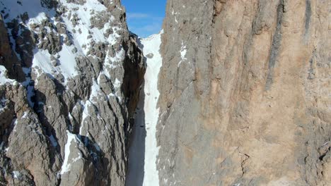 Filmischer-Drohnenflug-Zwischen-Dem-Gipfelloch-Der-Schneebedeckten-Berge-Und-Dem-Atemberaubenden-Blick-Auf-Die-Bergkette-Im-Hintergrund