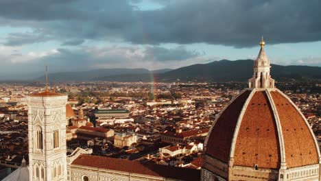 Rainbow-forming-behind-Florence-Cathedral-with-morning-sunlight-in-Italy,-aerial