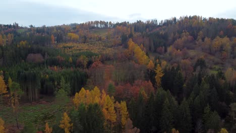 Fliegen-über-Buntem-Herbstlichem-Mischwald-Auf-Einem-Hügel-Mit-Bewölktem-Blauem-Himmel