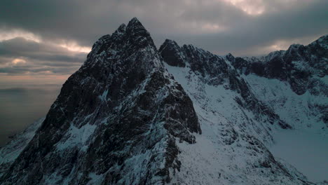 Dramatic-Lofoten-jagged-frozen-Svartvatnet-head-mountain-summit-aerial-view-orbiting-cold-sunrise-peaks
