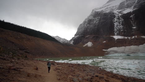 Young-Woman-Walking-by-Glacial-Lake-With-Icebergs-From-Angel-Glacier-Mount-Edith-Cavell,-Jasper-National-Park,-Canada