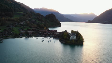 Cinematic-wide-rotating-aerial-shot-of-the-Iseltwald-Castle-on-Lake-Brienz-in-Switzerland-into-the-sun