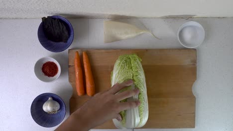 Male-hands-cutting-and-tearing-apart-cabbage-for-Kimchi-on-wooden-cutting-board