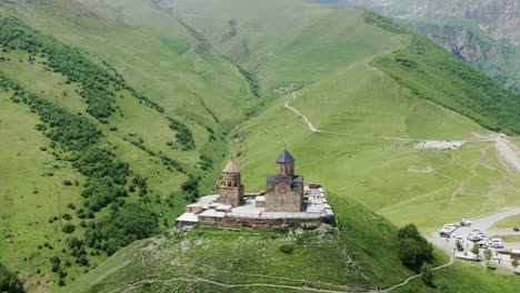 Gergeti-Trinity-Church-in-majestic-mountain-landscape,-cinematic-aerial-orbit-view