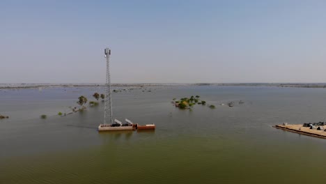 Aerial-Parallax-Shot-Around-Cell-Phone-Tower-Surrounded-By-Floodwaters-In-Jacobabad,-Pakistan