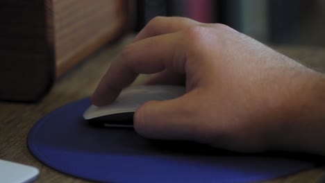 Man-uses-computer-mouse-with-blue-mouse-pad-close-up
