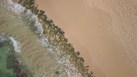 Aerial-shot-of-waves-crashing-on-rocky-shoreline