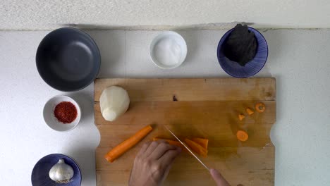 Male-hands-chopping-carrots-looking-down-on-cutting-board-in-kitchen