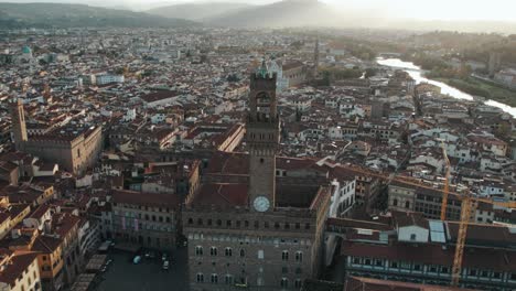 Palazzo-Vecchio-building-overlooking-Piazza-della-Signoria-during-sunrise,-Florence,-aerial