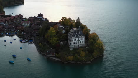 Cinematic-revealing-aerial-shot-starting-on-the-Iseltwald-Castle-then-going-wide-of-Lake-Brienz-in-Switzerland