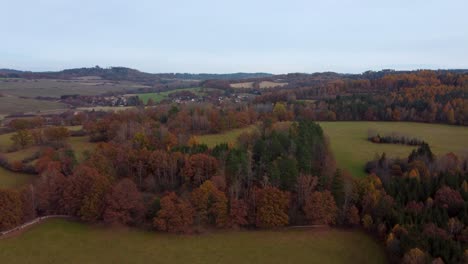Fliegen-über-Einer-Herbstlichen-Ländlichen-Landschaft-Mit-Feldern,-Wäldern-Und-Einem-Dorf