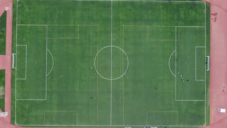 Aerial-bird's-eye-view-of-a-football-or-soccer-field-with-athletes-training-on-artificial-turf