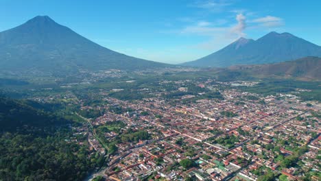 Antigua,-Guatemala-Con-Volcanes-Agua,-Acatenango-Y-Fuego-En-El-Fondo-Con-Una-Pequeña-Erupción-De-Humo