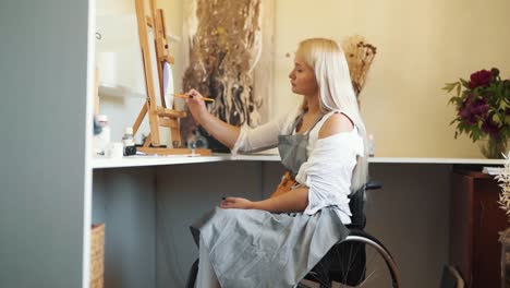 A-cute-fair-haired-girl-in-a-wheelchair-draws-on-the-glass