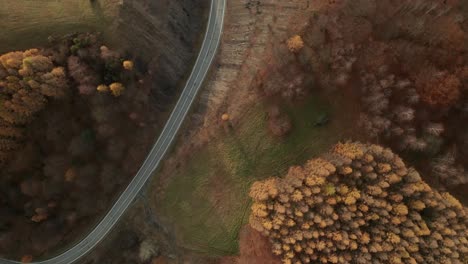 An-aerial-tilt-down-drone-view-of-a-winding-road-running-through-a-canyon-in-late-autumn