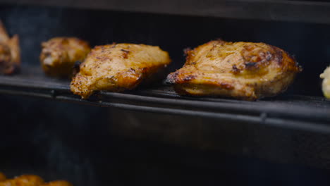 Close-Up-View-Of-Golden-Brown-Chicken-Pieces-On-BBQ-Grill-With-Smoke-Rising