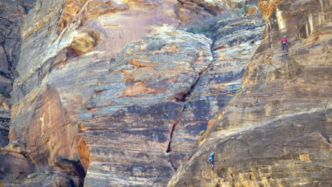 Telephoto-shot-of-two-rock-climbers-climbing-up-a-cliff-at-Zion-National-Park,-Utah,-United-States