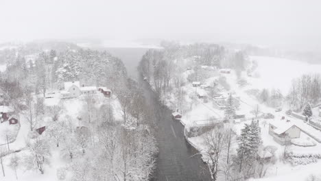 Aerial-view-overlooking-a-river-stream-and-a-lake-on-a-snowy-day-in-Sweden