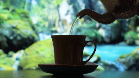 Gießen-Sie-Köstlichen-Tee-In-Eine-Kleine-Tasse-Mit-Der-Natur-Im-Hintergrund