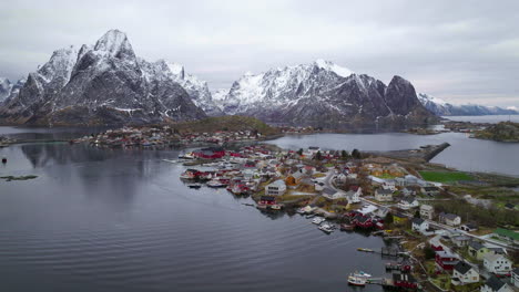 Moskenesøya-snow-capped-mountains-aerial-view-towards-idyllic-Reine-Norway-fishing-village