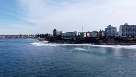 Aerial-shot-of-surfers-waiting-on-a-lineup-at-Cronulla-Point,-Sydney