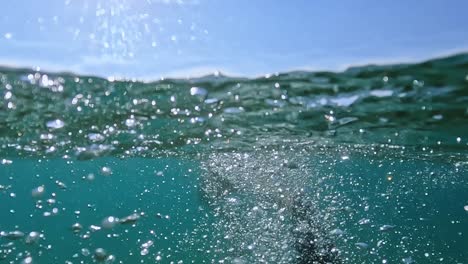 Geteilte-Unterwasser-Rückansicht-Des-Erwachsenen-Mannes,-Der-Mit-Tauchflossen-In-Kristallklarem-Meerwasser-Schwimmt