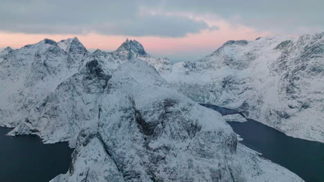 Lofoten-islands-extreme-wintry-frozen-mountain-and-blue-ocean-landscape-aerial-view-slowly-pulling-away