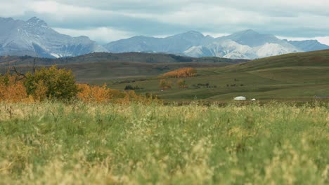 Beautiful-long-shot-of-the-farmland-in-prairies-with-the-Rocky-Mountains-on-background