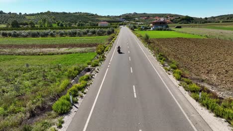 Motorcycle-riding-on-a-rural-road-near-farmland