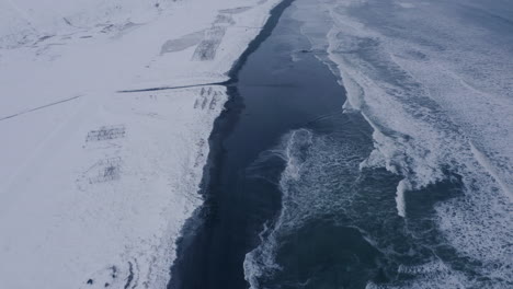 Aerial-flyover-Fish-racks-on-snowy-coast-of-Arctic-Ocean-in-Iceland-during-cloudy-day