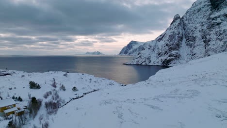 Snow-covered-Lofoten-islands-mountain-landscape-aerial-view-moving-forward-towards-blue-ocean-coast