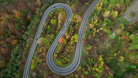 Aerial-view-of-a-winding-road-in-a-yellow-orange-and-green-autumn-forest-in-the-mountains-of-Bieszczady-in-Poland