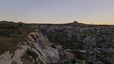 Göreme-Turkey-Aerial-v31-low-level-flyover-high-plateau-view-point-capturing-ancient-town-surrounded-by-landscape-of-rock-formations-with-sun-setting-at-horizon---Shot-with-Mavic-3-Cine---July-2022